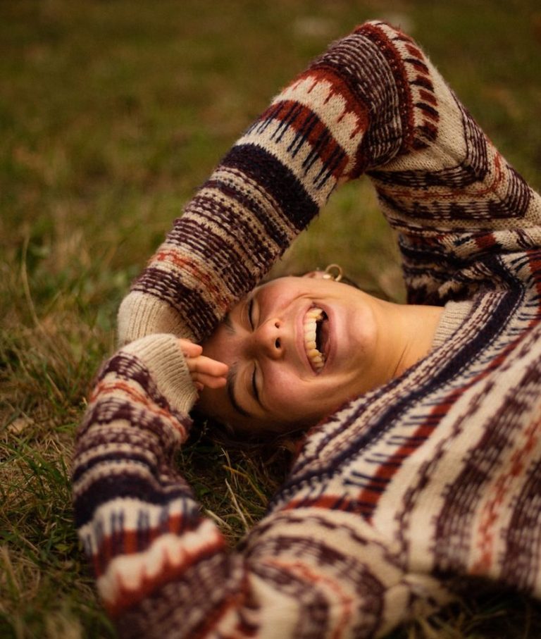 Leichtigkeit zurückholen Coaching nach Trennung und Krise Bild von einer Frau, die lachend im Gras liegt - Sinnbild für Leichtigkeit und Loslassen Maria Wadenpohl