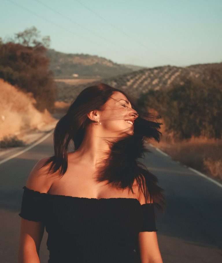 Selbstbestimmt zu Lebensfreude und Freiheit - Maria Wadenpohl Online-Coaching für Frauen nach Trennung und Krise Frau geht befreit auf Straße im Abendlicht, lacht und wirft den Kopf zurück - Sinnbild für Lebensfreude und Freiheit